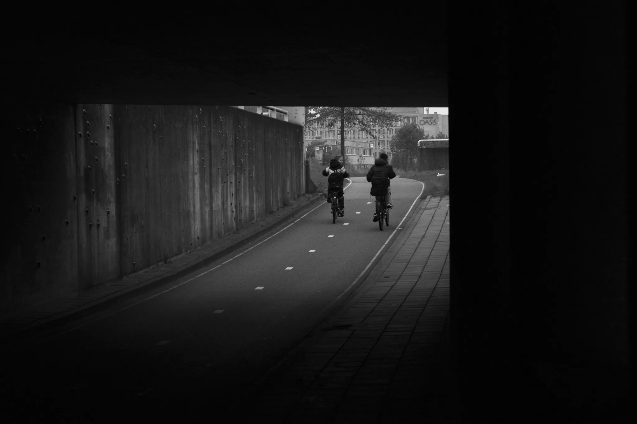 Street photography in the Netherlands Spijkenisse close to Carlton Oasis in B&W of two kids on a bike.