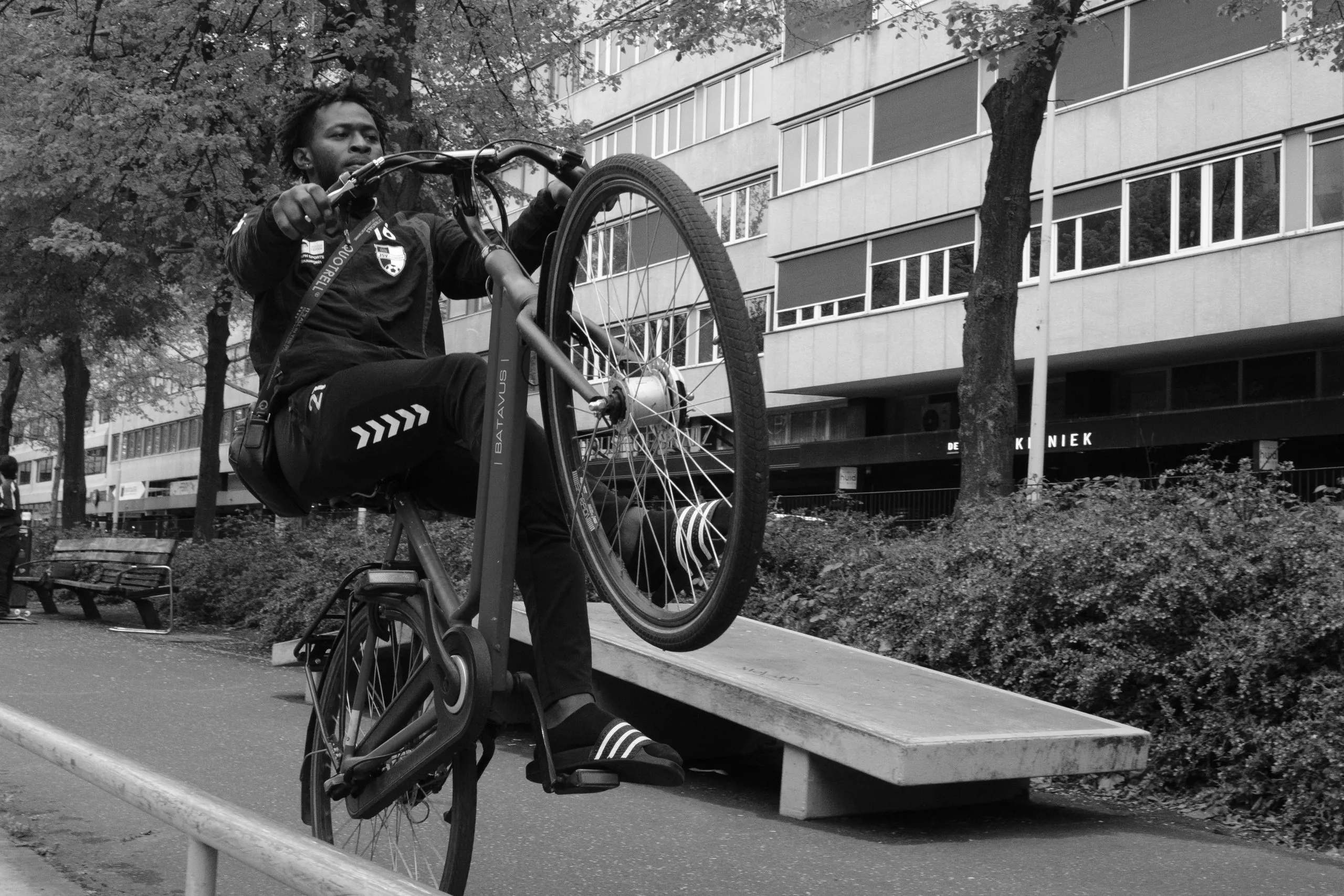 Street photography in Rotterdam the Netherlands of a biker riding his bike on one wheel in B&W.