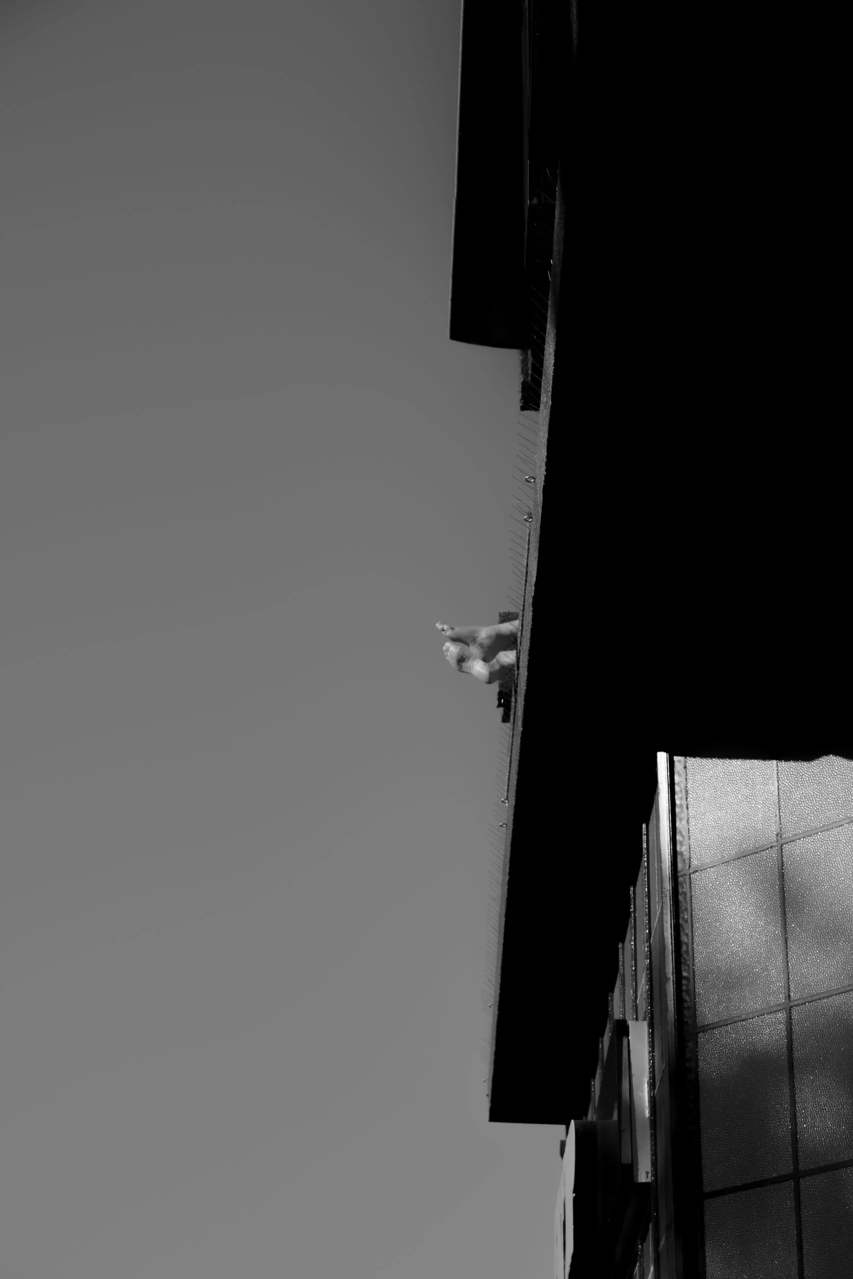 Street photography in the Netherlands Schiedam of two feet sticking out of a building in B&W.