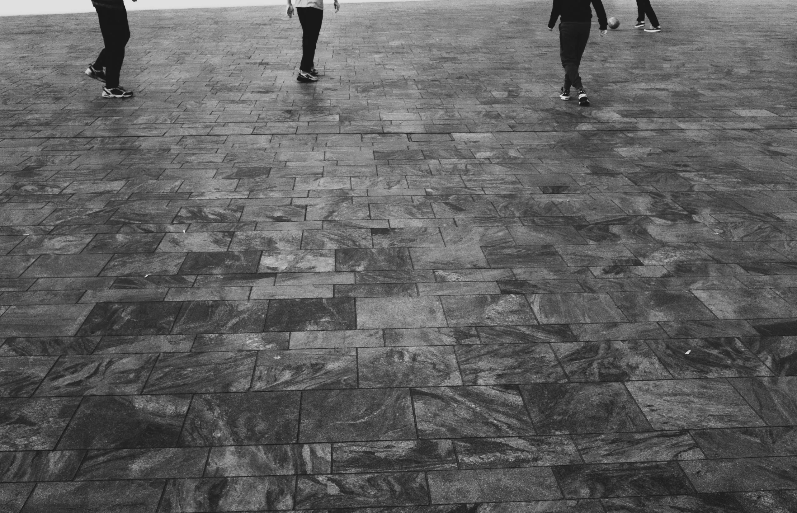 Street photography in the Netherlands Rotterdam Central station of young man playing soccer in B&W.
