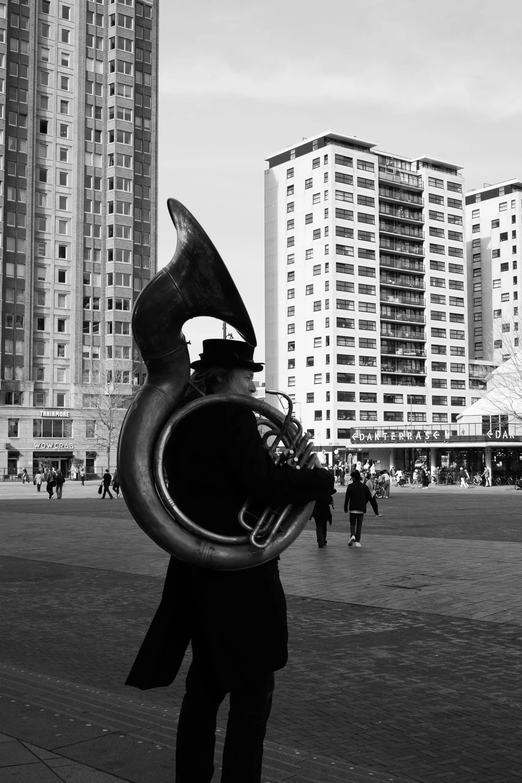 Street photography in the Netherlands Rotterdam close to markhal of a man playing trombone in B&W.