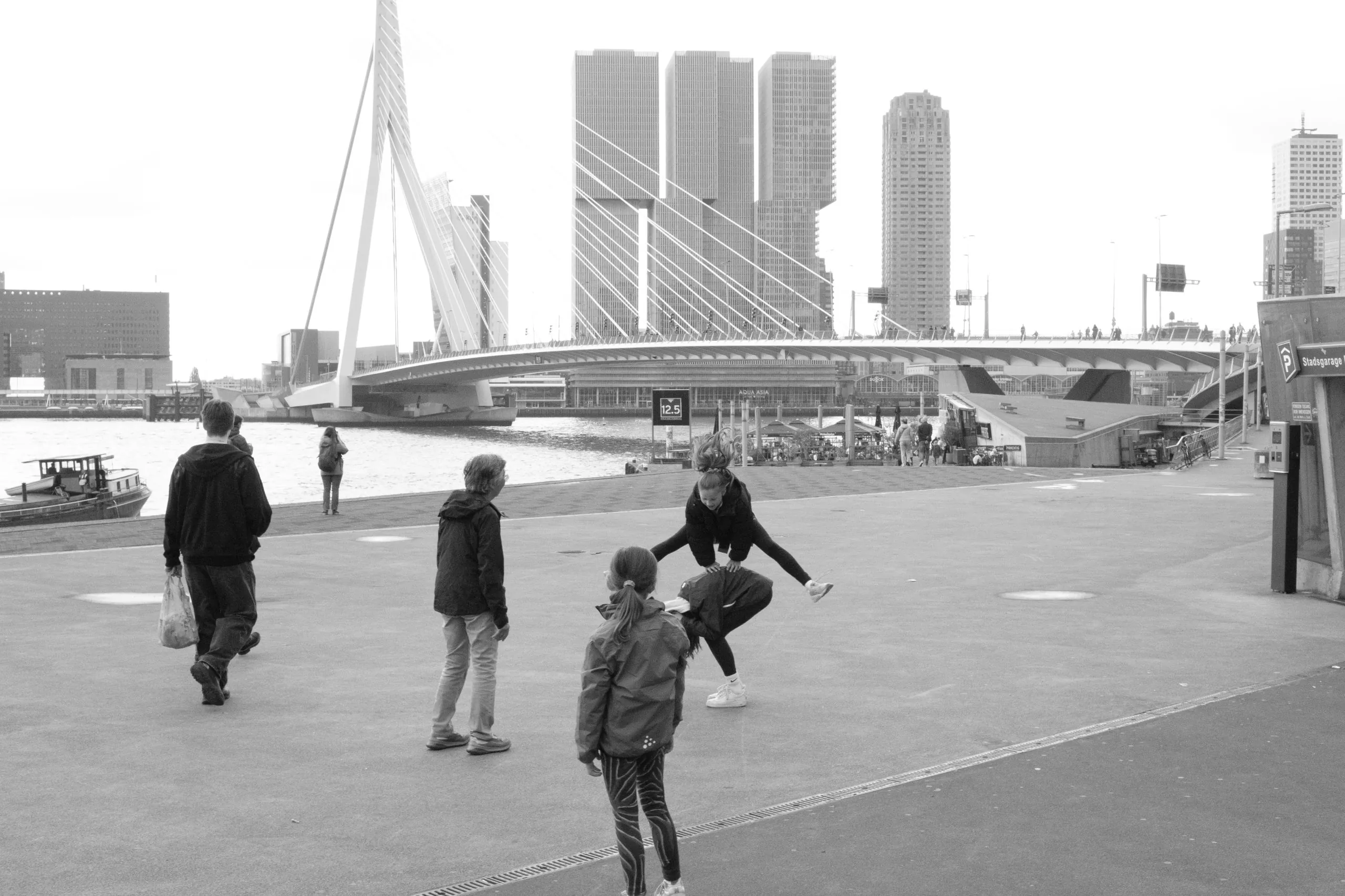 Street photography in Rotterdam the Netherlands at the erasmusbrug of jumping kids in B&W.