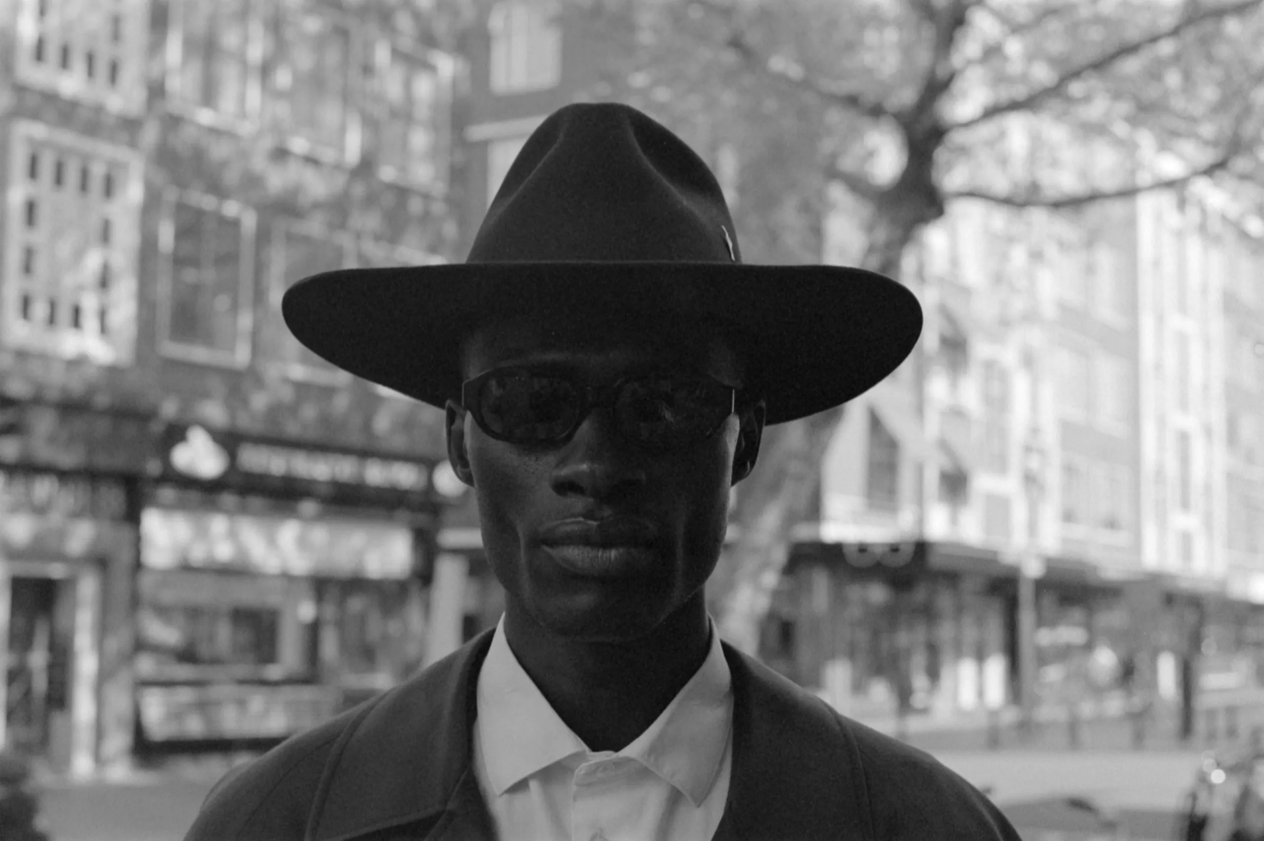 Street photography in Rotterdam de meent of a man with a hat a glasses posing taken on 35mm film B&W.