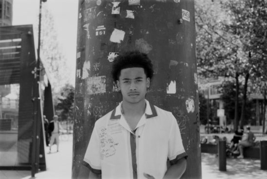 Man posing at pole with markings shot on black and white 35mm film trix400.