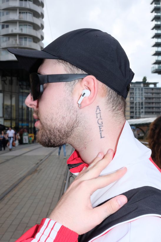 Man showing his tattoo "Angel" in his neck, photo taken on XE-3 on camera flash.